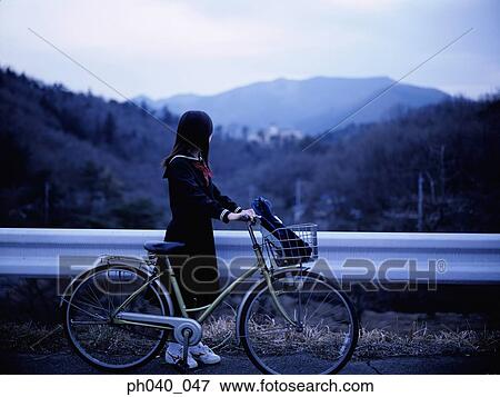 Stock Photo - School girl holding a bicycle. Fotosearch