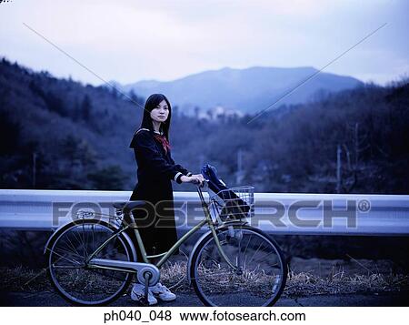 Stock Photo - School girl holding a bicycle. Fotosearch