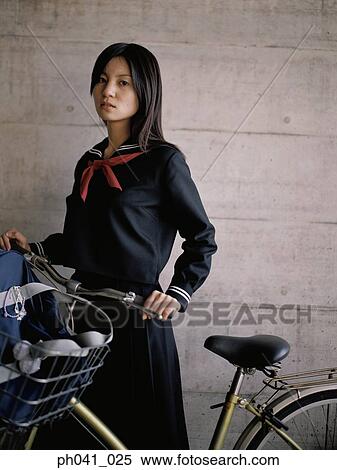 Stock Photography - School girl holding a bicycle. Fotosearch