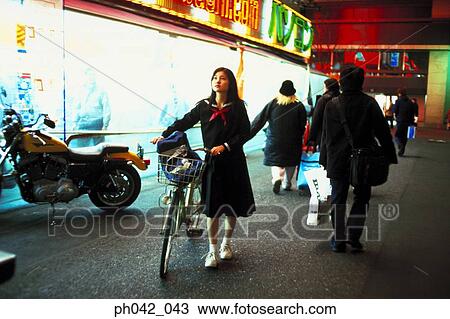 Stock Image - School girl pushing a bicycle. Fotosearch