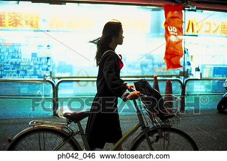 Stock Photograph - School girl pushing a bicycle. Fotosearch