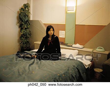 Stock Image - School girl sitting on a bed. Fotosearch