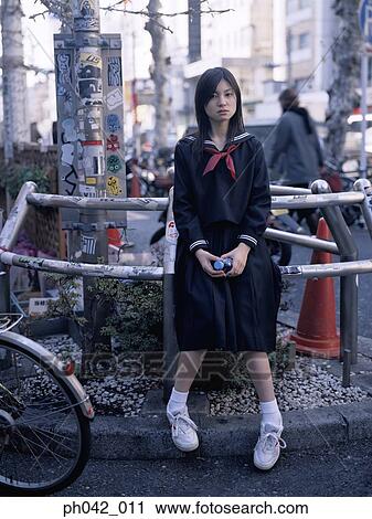 Stock Image - School girl sitting on a metal railing. Fotosearch