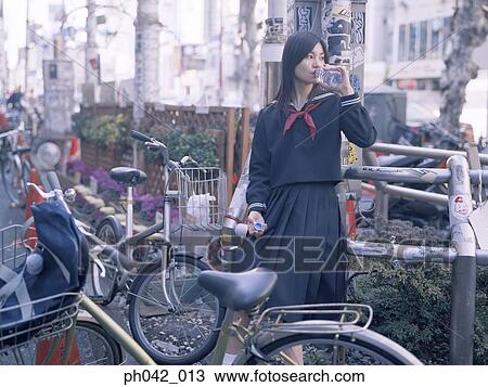 Stock Image - School girl sitting on a metal railing. Fotosearch