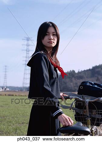 Stock Photo - School girl holding a bicycle. Fotosearch