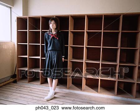 Stock Image - School girl leaning against a shelve. Fotosearch