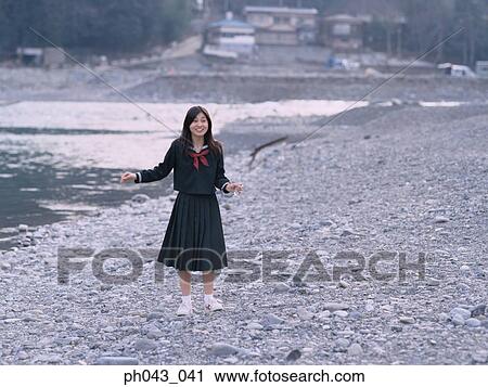 Stock Image - School girl standing along the river bed. Fotosearch