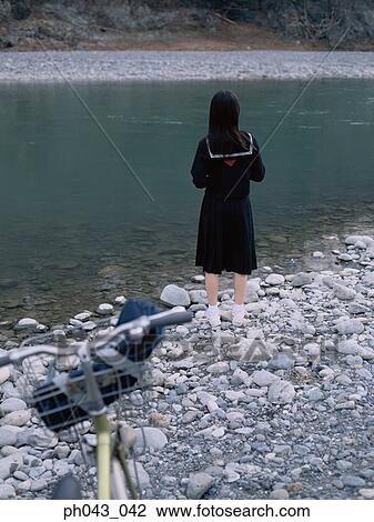Stock Image - School girl standing along the river bed. Fotosearch
