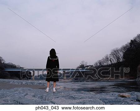Stock Image - School girl standing along the river bed. Fotosearch