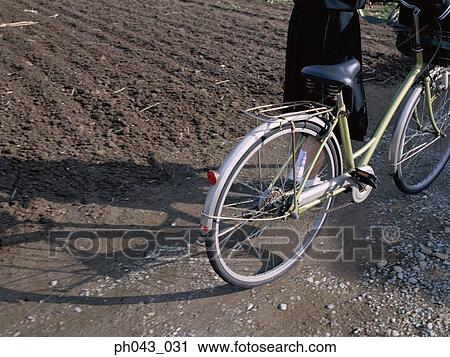Woman pushing a bicycle View Large Photo Image Stock Image - Woman pushing a bicycle. Fotosearch
