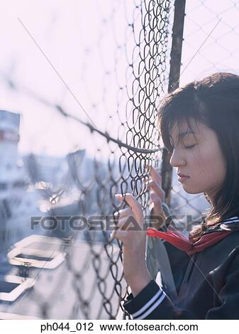 Stock Image - School girl holding on the fence. Fotosearch