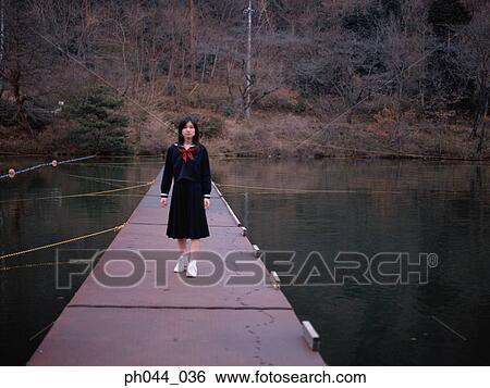 Stock Photograph - School girl standing on the pathway. Fotosearch