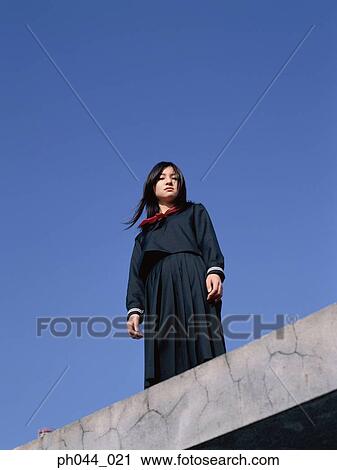 Stock Image - School girl standing on the roof top. Fotosearch
