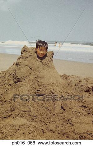 Boy buried in a pile of sand View Large Photo Image Stock Photo - Boy buried in a pile of sand. Fotosearch