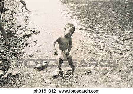 Stock Image - Boy playing in the river bank. Fotosearch