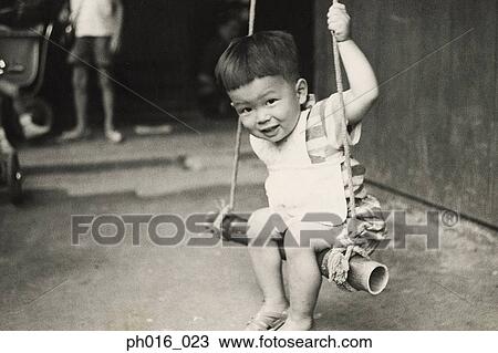 Stock Image - Boy playing on a swing. Fotosearch