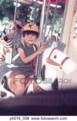 Stock Photo - Boy sitting on a merry-go-round ride. Fotosearch