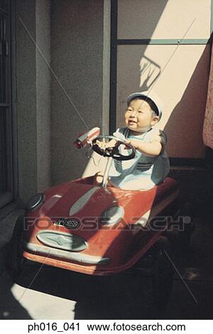 Stock Image - Boy sitting on a toy car. Fotosearch