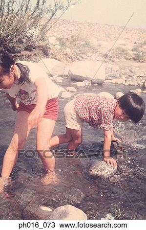 Stock Image - Children playing on riverbank. Fotosearch