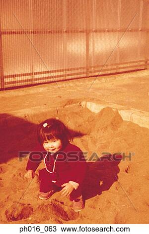 Stock Image - Girl building sand castle. Fotosearch