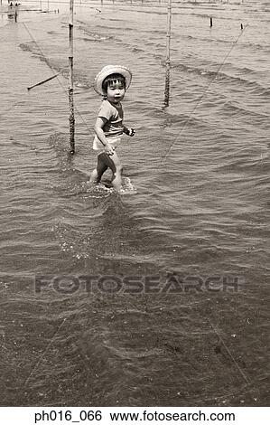 Stock Photograph - Girl playing on river bank. Fotosearch