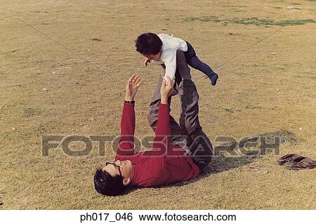 Stock Photograph - Father and son playing in a park. Fotosearch