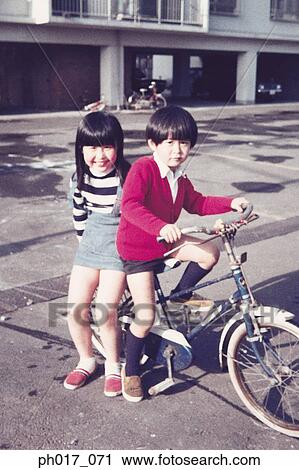 Stock Image - Sister, brother and bicycle. Fotosearch