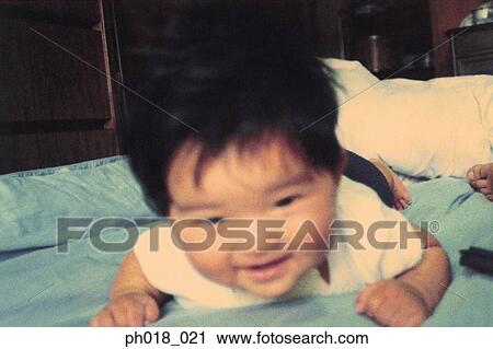 Stock Image - Baby crawling on bed. Fotosearch