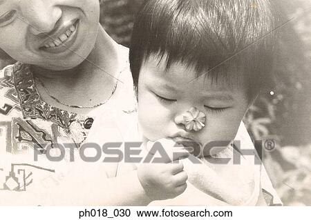Mother carrying baby holding a flower View Large Photo Image Stock Image - Mother carrying baby holding a flower. Fotosearch