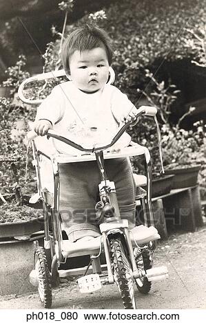 Stock Image - Portrait of a baby girl in tricycle. Fotosearch