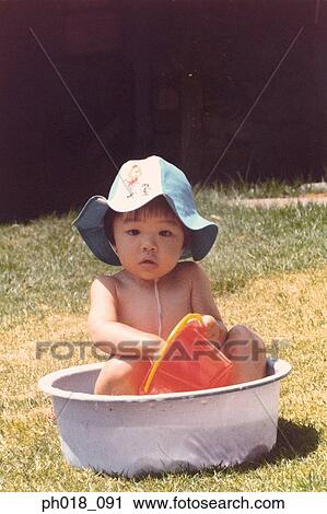 Stock Image - Portrait of a baby girl playing water in the garden. Fotosearch