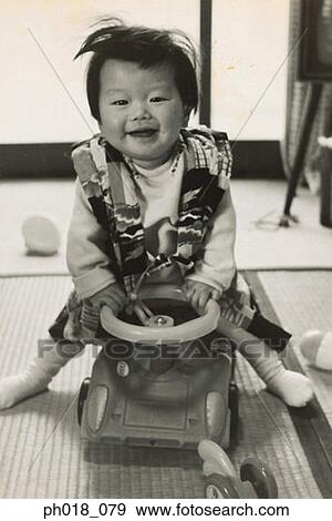 Stock Photo - Portrait of a baby girl sitting on the toy car ride. Fotosearch