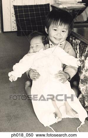 Stock Image - Portrait of brother carrying a baby. Fotosearch