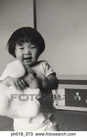 Stock Image - Young girl playing with doll. Fotosearch