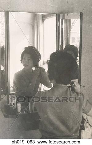 Stock Image - An Asian woman brushing her hair. Fotosearch