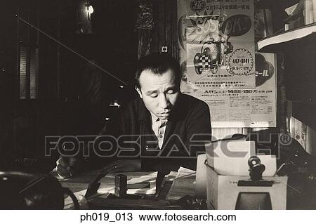 Stock Image - Asian man holding a pen in the room. Fotosearch