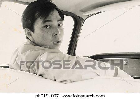 Stock Photo - Asian man in the passenger seat of a car. Fotosearch