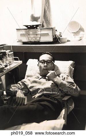 Asian man resting on sofa View Large Photo Image Stock Photo - Asian man resting on sofa. Fotosearch