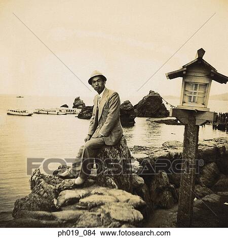 Young Asian man sitting on the rocks View Large Photo Image Picture - Young Asian man sitting on the rocks. Fotosearch