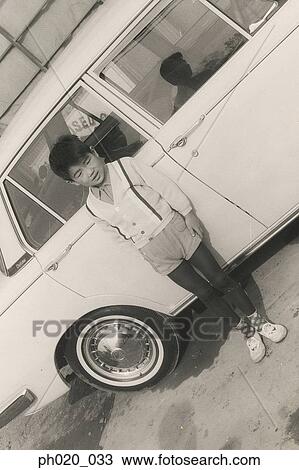 Stock Image - Portrait of a boy leaning against car. Fotosearch
