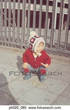Stock Photography - Portrait of a girl squatting at passage way. Fotosearch