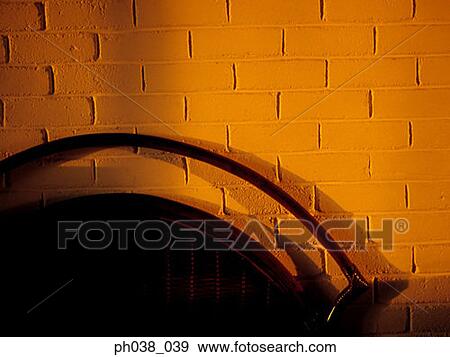 Stock Photo - Silhouetted bench and orange brick wall. Fotosearch