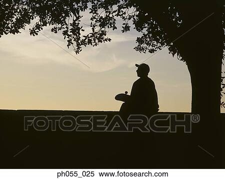Silhouette of a young man sitting holding skateboard View Large Photo Image Stock Photography - Silhouette of a young man sitting holding skateboard. Fotosearch