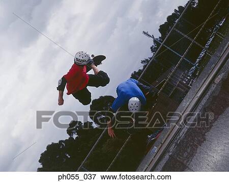 Stock Photo - Two young skateboarders in mid air. Fotosearch
