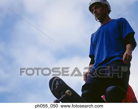 Young male standing on ramp holding skateboard View Large Photo Image Stock Image - Young male standing on ramp holding skateboard . Fotosearch