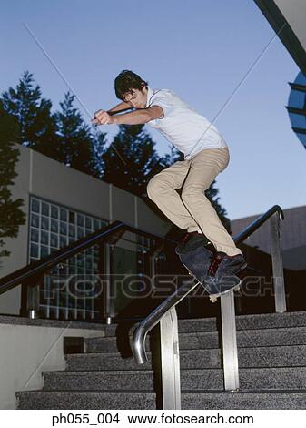 Picture - Young man skateboarding down railing . Fotosearch