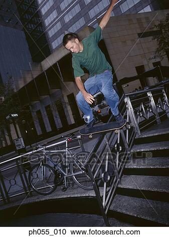 Young man skateboarding down railing View Large Photo Image Stock Image - Young man skateboarding down railing . Fotosearch