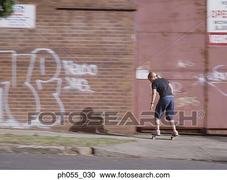 Young man skateboarding down the street View Large Photo Image Stock Image - Young man skateboarding down the street. Fotosearch