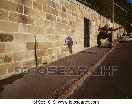 Young man skateboarding down the street View Large Photo Image Stock Photo - Young man skateboarding down the street. Fotosearch