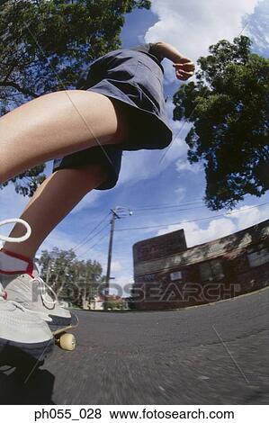 Stock Photo - Young man skateboarding down the street. Fotosearch